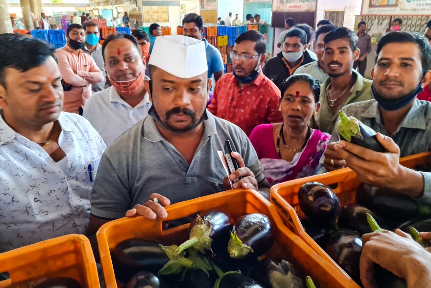 At a wholesale government market in western India, auctioneer Sanjay Gangurde takes down bids from traders for crates of glistening eggplants.