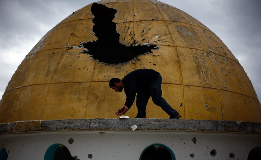 A Palestinian man picks up fragments of a mosque's golden dome, which was hit by a tank round during the fighting between Hamas and Israeli forces, north of Gaza City on Jan. 20, 2009.