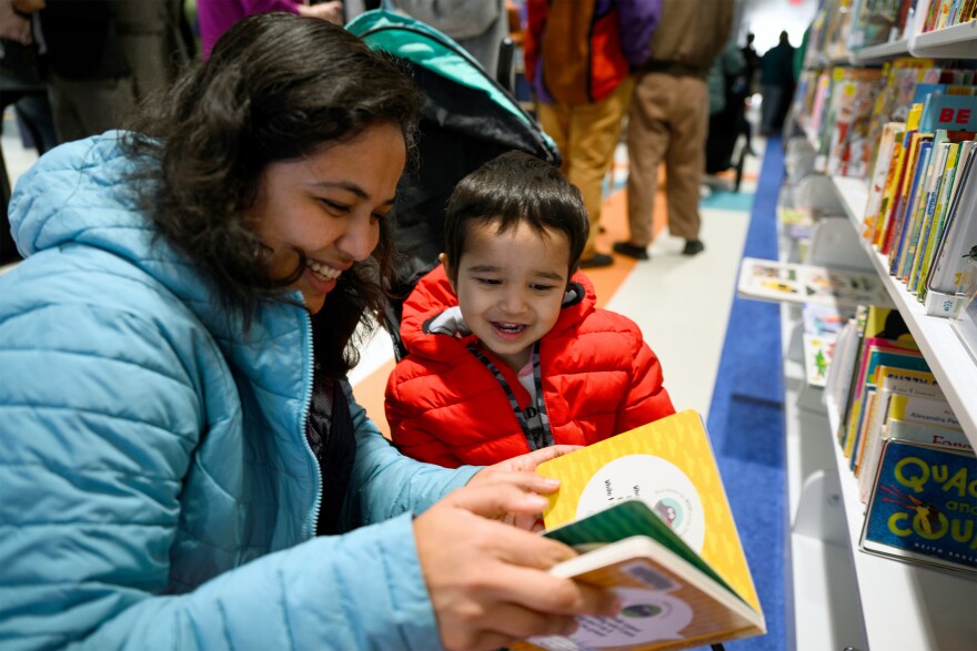 Meghana Pai reads a book to her 2-year-old son Naman Nayak at the reopening of the Hartford Public Library’s downtown branch. She said they live nearby and have been waiting a long time to be able to access the library. “It’s especially helpful for the winter time,” she said. “To learn new skills, make friends, get the stepping stones for learning.”