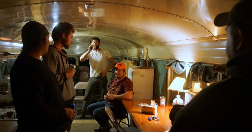 A bunch of guys drinking beer in a school bus.  