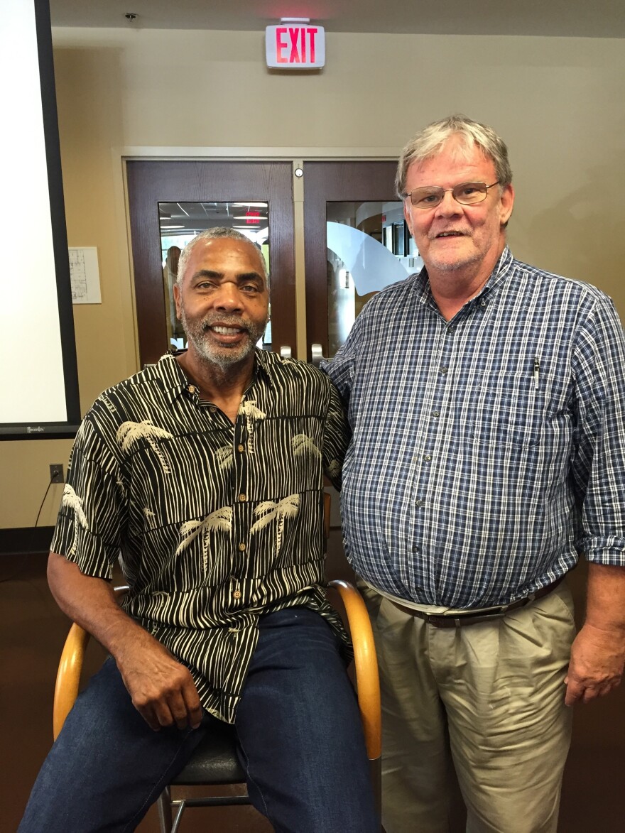 two men face the camera smiling