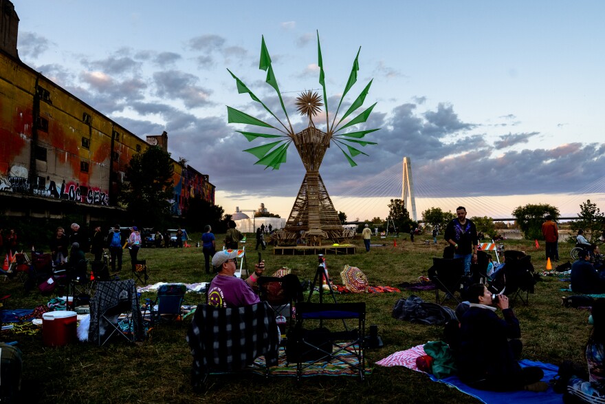 Dozens of festival goers wait for “Our Lady of Artica” to be set ablaze Sunday, Oct. 8, 2023, during the Artica Urban Art Festival along the Mississippi Riverfront in downtown St. Louis.