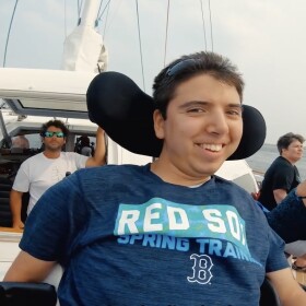 Young man with a disability, Samuel Habib, on a boat smiling