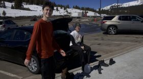 Two people sit behind a car