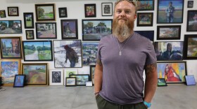 Painter Wyatt LeGrand Poses in front of a wall covered in his piantings.