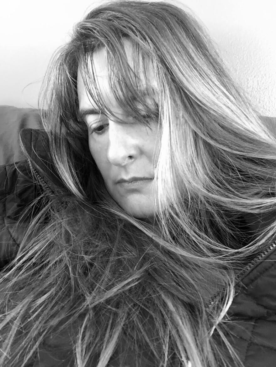 A woman with long hair looks down. 