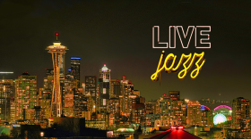 A photo of the Seattle skyline, including the Space Needle, with a neon live jazz sign.
