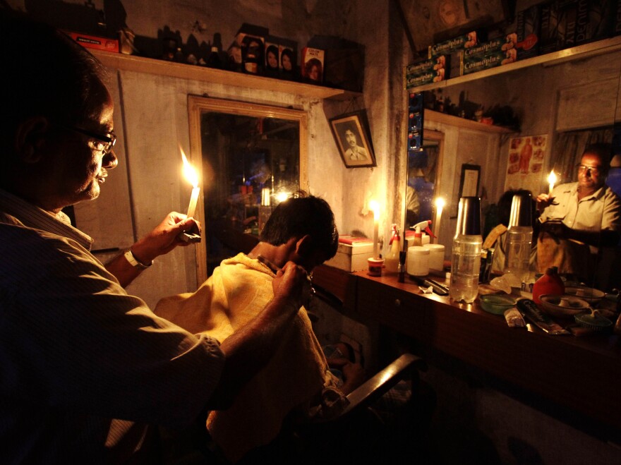 During the blackout on Tuesday, an Indian barber cut hair by candlelight in his shop in Kolkata.