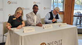 Nicolet College President Kate Ferrell, Director of the Wisconsin Bureau of Apprenticeship Standards David Polk, and Sokaogon Chippewa Community Chairman Robert VanZile sit at a table at the college signing an agreement that will launch a Broadband Service Technician apprenticeship program.