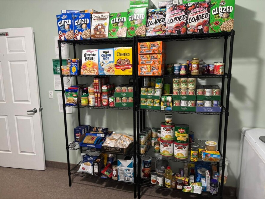 Shelves are filled with food items like cereal, pasta and canned vegetables.