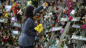 Holly Harmon places a rose into a memorial for victims of Hurricane Ian in Fort Myers, Fla., on Monday, Oct. 10, 2022. More than 100 died during the hurricane, with the greatest number in Lee County. (AP Photo/Jay Reeves)