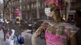 Shoppers in masks pass a store with a masked mannequin in Barcelona, Spain, on Saturday, March 14.