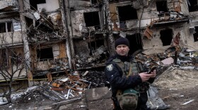 A Ukrainian police officer stands in front of a damaged residential block hit by an early morning missile strike on February 25, 2022 in Kyiv, Ukraine. (Chris McGrath/Getty Images)
