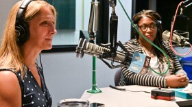 Two women sit in a radio studio talking at microphones.