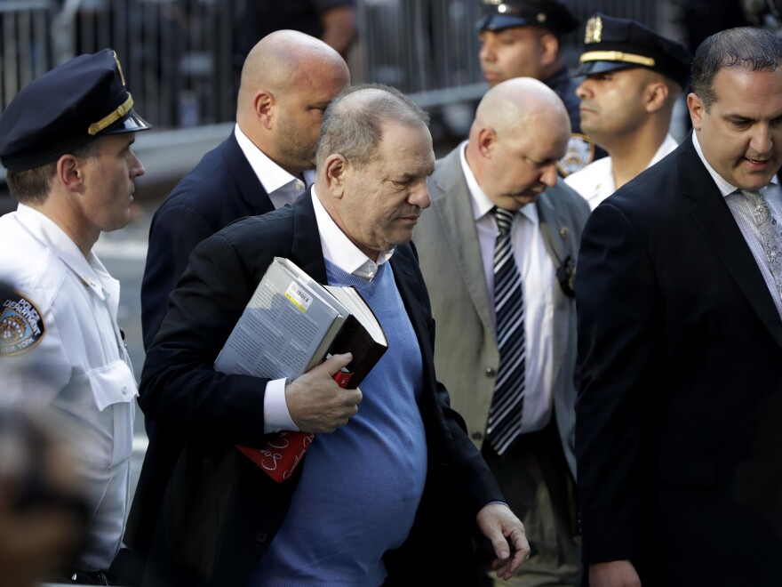 Harvey Weinstein, seen earlier Friday morning, walks into the Manhattan police station flanked by law enforcement and surrounded by members of the media.