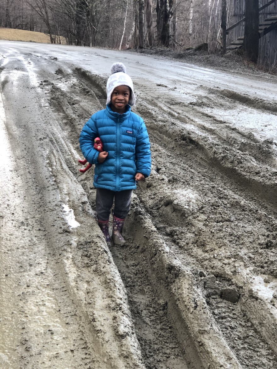 A picture of a child standing in a muddy brown road