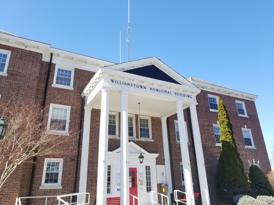 A brick building with white columns sits under a blue sky