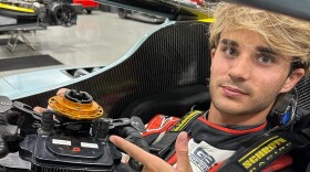 Young man with blond hair in a race car. 