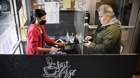 Server Amber Beecher, left, completes a sale with a customer behind a plexiglass partition at Rodd's Restaurant, Thursday, Dec. 10, 2020, in Bristol, Conn. Small restaurant owners in Connecticut are taking out loans, forgoing their paychecks and charging on credit cards to remain in business as the coronavirus pandemic continues.