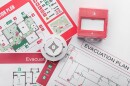 Evacuation plans, smoke detector and manual call point on white background