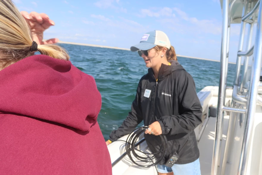 Hannah Leary, ecotourism coordinator for the Atlantic White Shark Conservancy, lowers a hydrophone into the water to listen for an acoustic tag on a great white shark, Sept. 12, 2025.