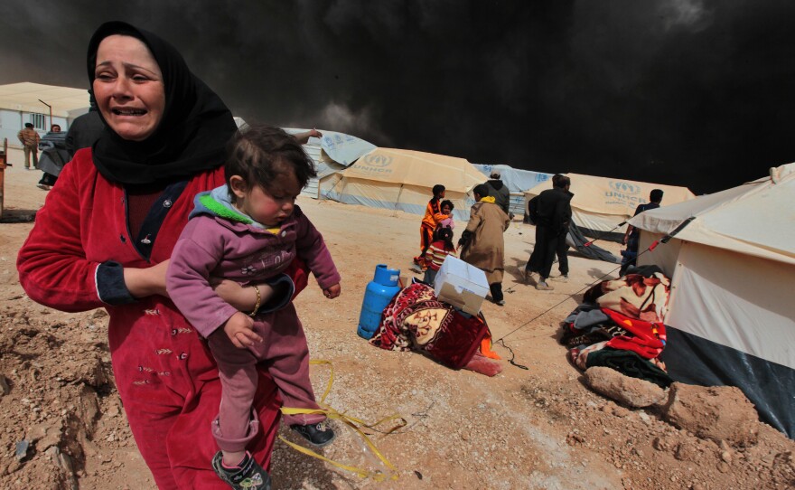 A woman carries her child to escape from the burnt tents at Zattari Syrian refugee camp near Mafraq, Syria, on March 8. A heavy fire broke out and consumed a large number of tents. UNICEF reports that more than two million Syrian children are internally displaced refugees within Syria.