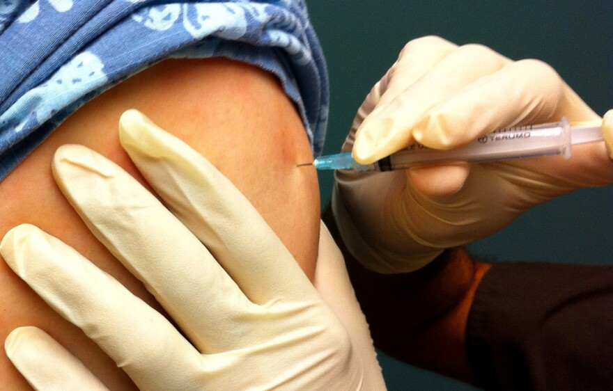 An injection is administered to the upper arm.