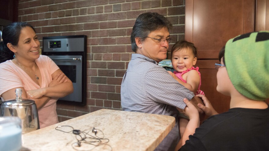 Carballo's wife, Carla Naranjo, and his son look on as he holds his 1-year-old daughter, Reina de la Paz. Her name means "queen of peace" in Spanish.