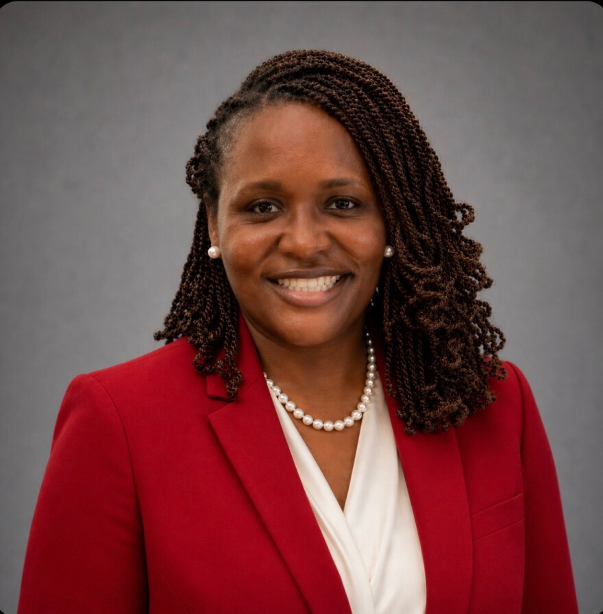 A woman in red suit smiles for the camera.