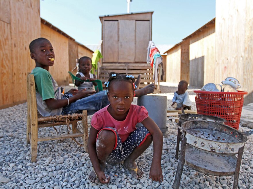 Children play in front  of latrines built by the American Red Cross at the camp near Cite Soleil.