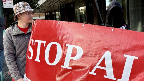 Yakko and a masked protester hold a banner that says "STOP AI"