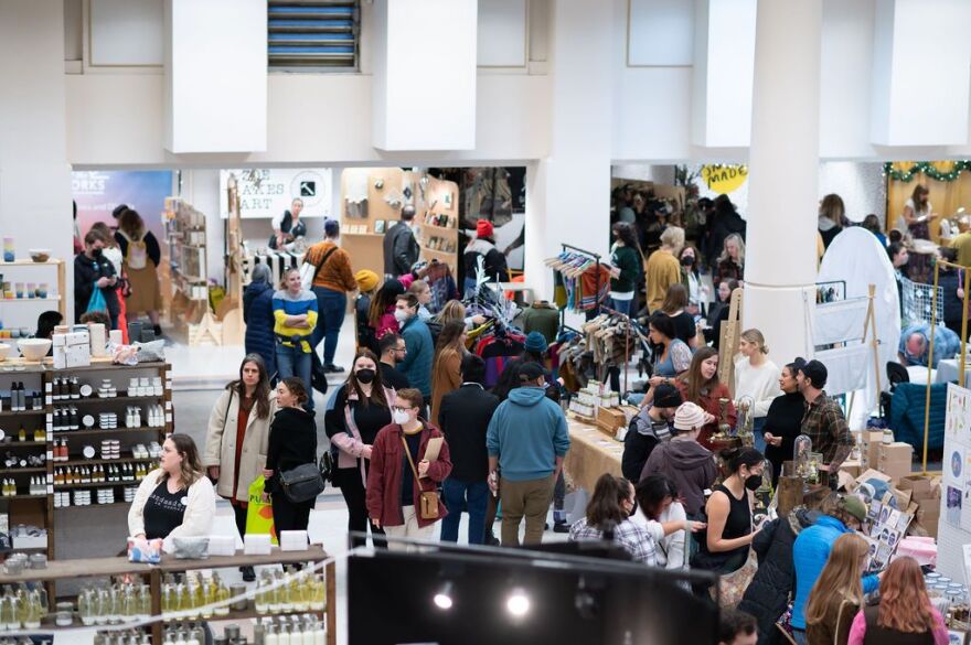 A crowd of people shopping around at different vendor stalls.