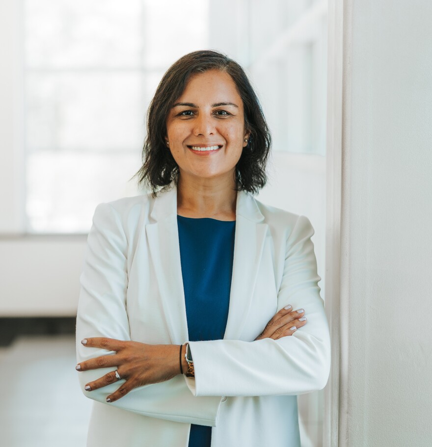 An instructor for the University of South Florida poses for a headshot in a white blazer. 