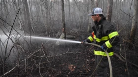 Firefighter Peter Curto soaks the ground at the site of a wildfire in Braintree last Friday.