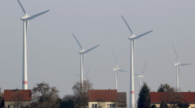 Wind turbines stand behind houses of the village of Feldheim near Berlin, Germany. (Michael Sohn/AP)