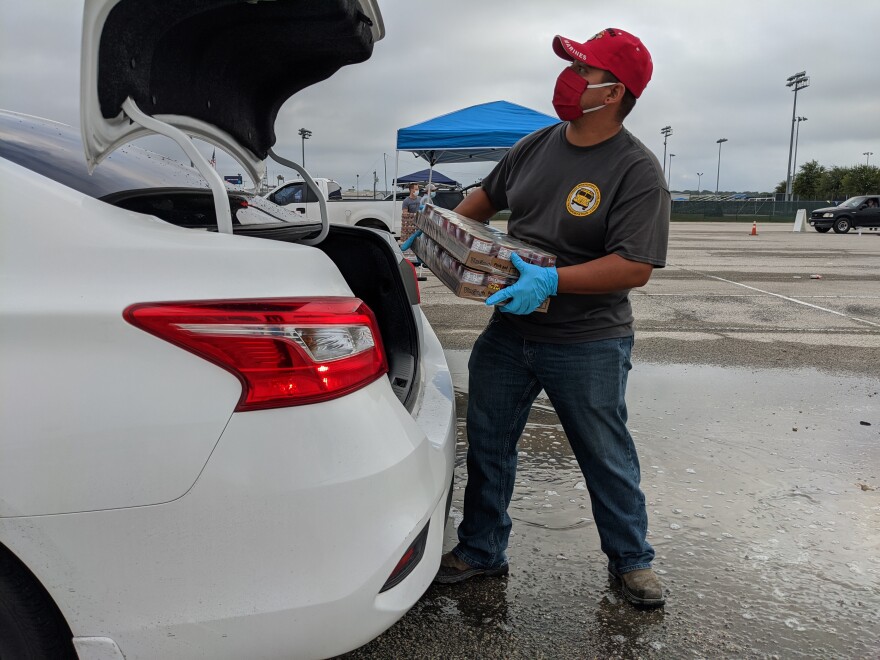 A volunteer loads food into a vehicle at a food distribution event in San Antonio.