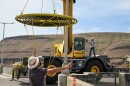 A crew lifts a fish bubbler, which looks like concentric  circles of hose, with a crane.