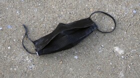 A dirty used protective face mask is abandoned on the ground in the Tuileries garden, in Paris, France, Monday, March 14, 2022. France has lifted most COVID-19 restrictions on Monday, allowing people to remove face masks in almost all places and allowing those unvaccinated back into restaurants, sports arenas and other leisure venues. (AP Photo/Francois Mori)