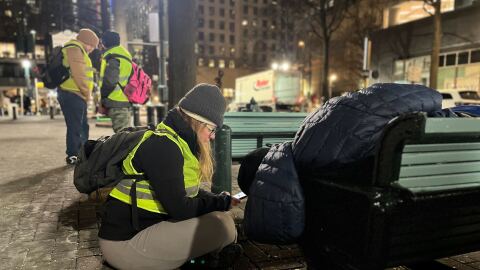 A surveyor, talking to a homeless man, in uptown Charlotte on Jan. 23.