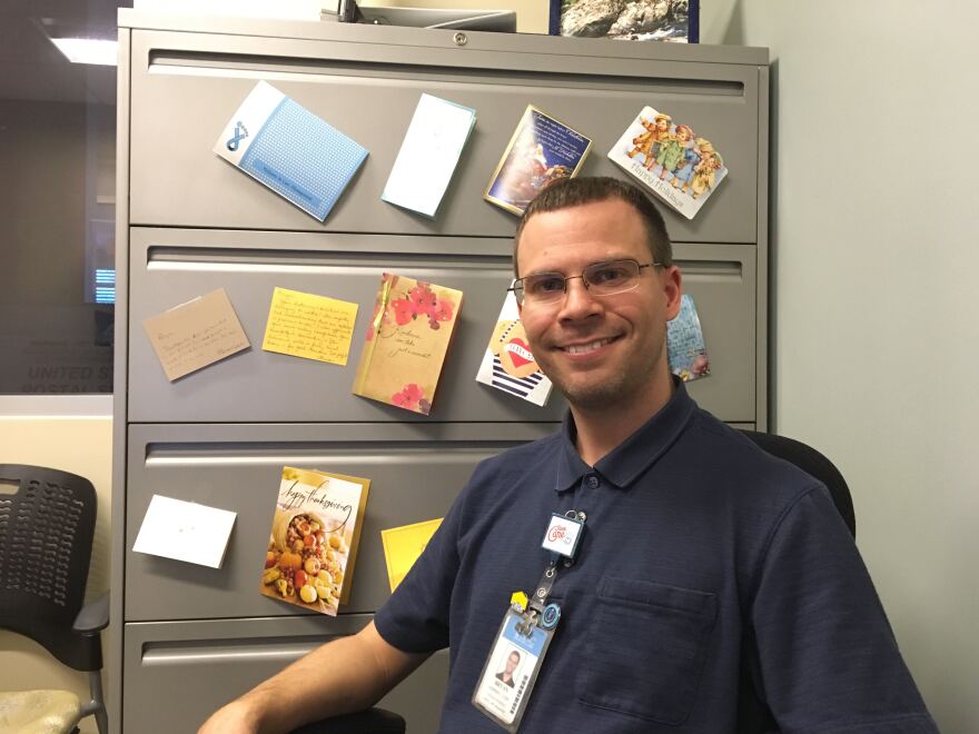 Geriatrics Social Worker Bryan Godfrey hangs thank-you cards from clients in his office.