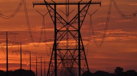 The sun begins to rise near power lines 