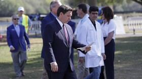 FILE- In this March 23, 20202 file photo, Florida Gov. Ron DeSantis, center front, arrives at a mobile testing site for a press conference Monday, March 23, 2020, in The Villages, Fla. The Villages, a retirement community, is one of the largest concentration of seniors in the U.S. Republican Gov. Ron DeSantis has been walking a tightrope for weeks during the coronavirus crisis, trying to protect both Floridians vulnerable to the virus and the cratering economy in a state of 21 million people. (AP Photo/John Raoux, File)
