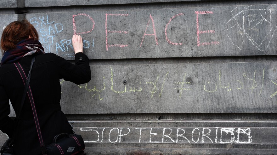 A woman writes a message on a wall in tribute to victims in Brussels on Wednesday, a day after deadly explosions struck the Belgian capital.