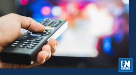 Person holding remote control in front of television screen
