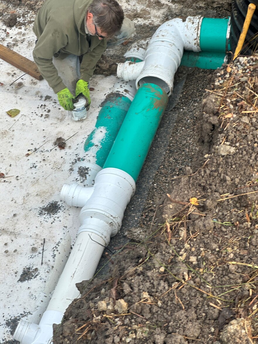 A man bends over a line of pipe.