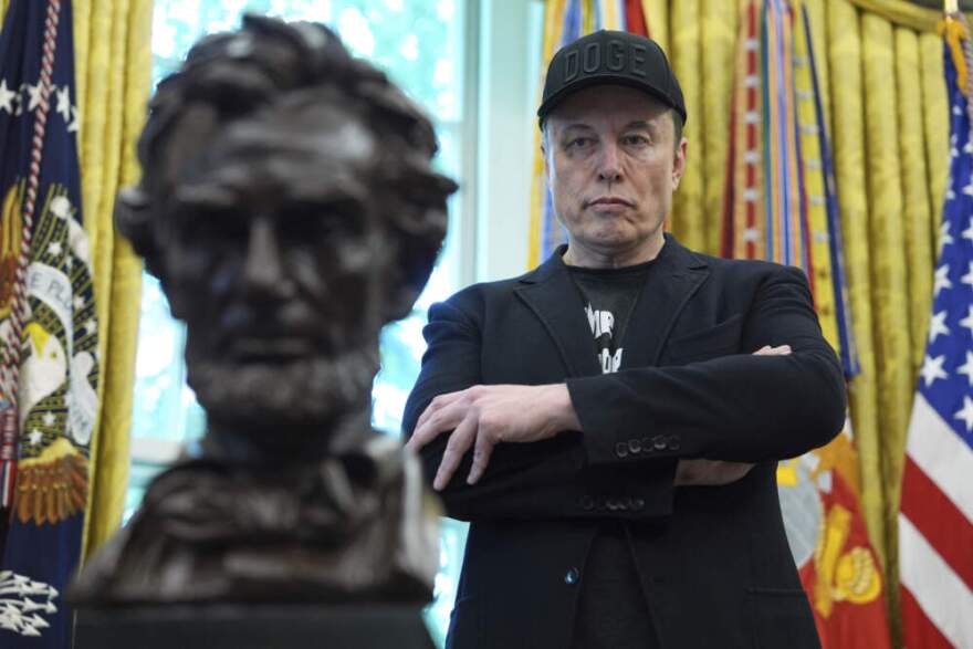 Elon Musk listens as President Donald Trump speaks during a news conference in the Oval Office of the White House, May 30, 2025, in Washington. (Evan Vucci/AP)