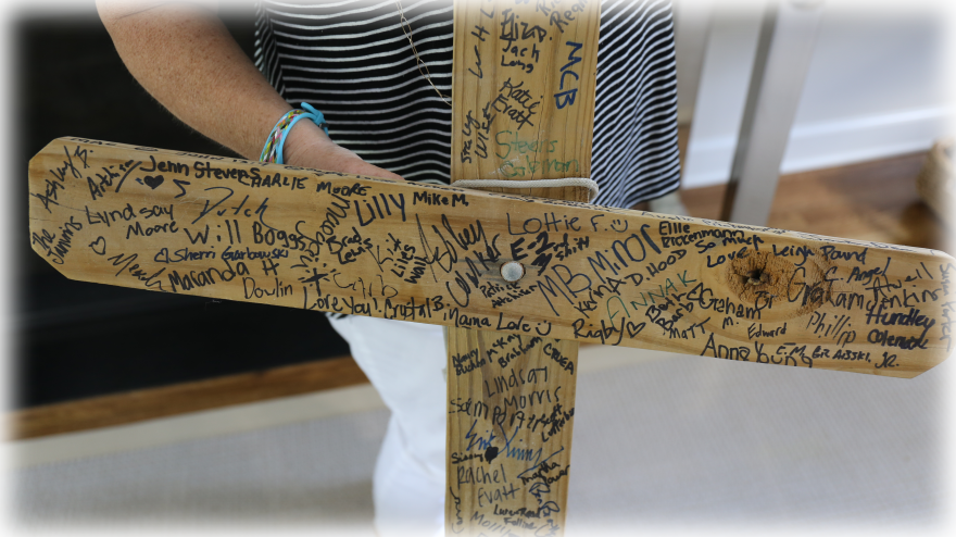 Julie Latham keeps this cross, signed by Lake Katherine community members, as a memento of community support after October’s flood.