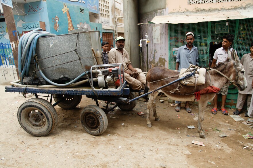 A man delivers a small tanker of water lashed to his donkey cart in the Korangi slum in Karachi.