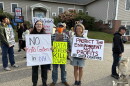Three people pose holding signs against data centers.