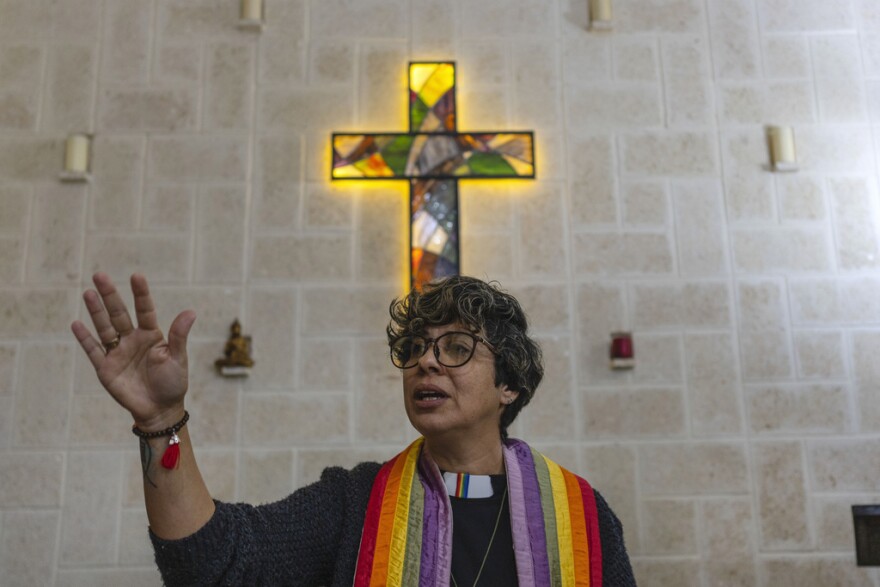 A woman wearing a rainbow-colored clergy stole.